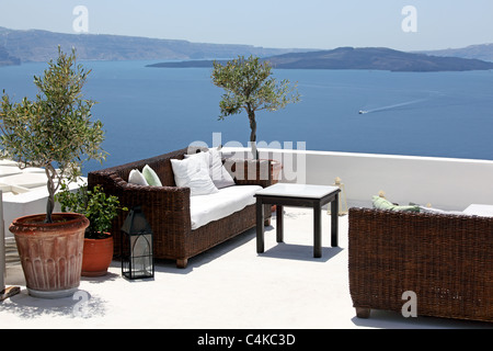 Table d'extérieur et canapés sur terrasse avec vue sur mer, le village d''Oia, Santorini, Cyclades, en Grèce. Banque D'Images