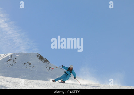 Un skieur se sculpte un tour sur piste dans la station de ski française de Courchevel. Banque D'Images