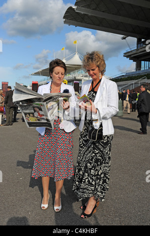 Femme Racegoers lors d'une soirée de Goodwood en juin lire le Racing Post essaie de choisir un gagnant UK Banque D'Images