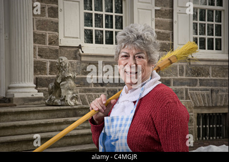 Femme tenant un balai à l'extérieur de vieux Home Banque D'Images