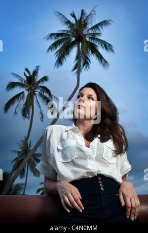 Portrait d'un modèle s'appuyant sur un balcon en face de palmiers Banque D'Images