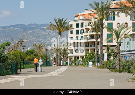 Couple touristes visiteurs marchant le long de la promenade entre Le Lido et Praia Formosa Funchal Madère Portugal Europe Banque D'Images