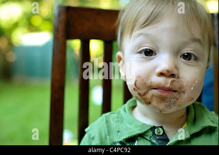 1-year-old boy on premier anniversaire avec glaçage à gâteau sur le visage Banque D'Images