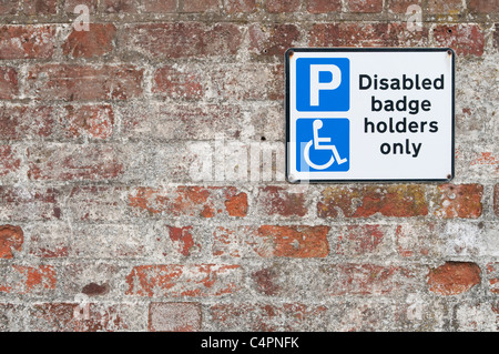 La plaque de stationnement pour handicapés sur mur de brique, Suffolk, UK. Banque D'Images