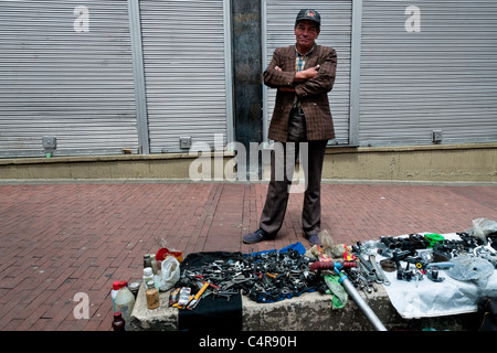 Un homme se tient au service d'un dispositif de réparation de bicyclettes boutique sur la rue pendant la journée sans voiture à Bogota, Colombie. Banque D'Images