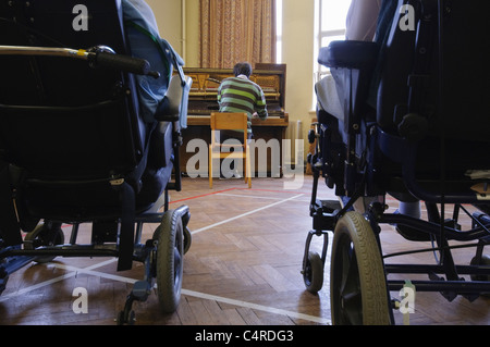 Un homme joue du piano dans un hôpital ou hospice pour personnes handicapées Banque D'Images