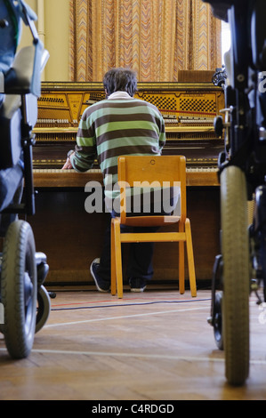 Un homme joue du piano dans un hôpital ou hospice pour personnes handicapées Banque D'Images