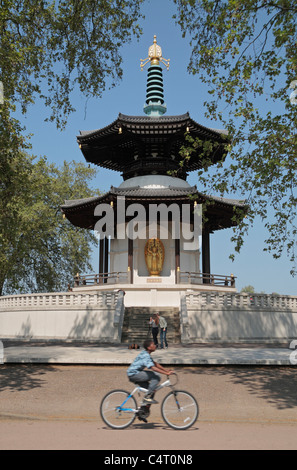 Un jeune cycliste en passant en face de la Pagode de la paix bouddhiste japonaise, Battersea Park, London, UK. Banque D'Images