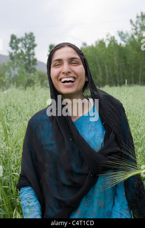 Femme cachemire rire en face de champs d'herbe près de Manasbal Lake, dans l'état de Jammu-et-Cachemire, l'Inde Banque D'Images