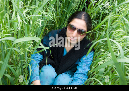 Cachemire femme porte des lunettes de soleil dans l'herbe près de champs Manasbal Lake, dans l'état de Jammu-et-Cachemire, l'Inde Banque D'Images