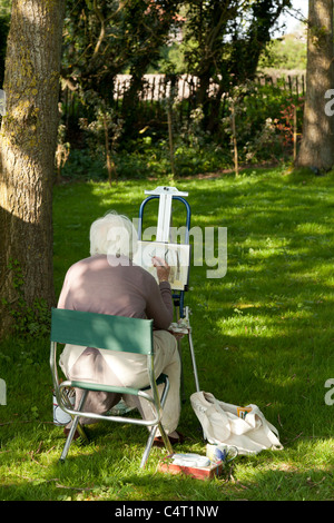 Artiste sur la selle la peinture sous quelques arbres sur une journée ensoleillée Banque D'Images