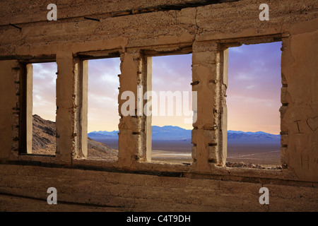 En regardant à travers les fenêtres d'une structure en ruine surplombant l'Amargosa Valley, Nevada Rhyolite à une ville abandonnée près de Banque D'Images