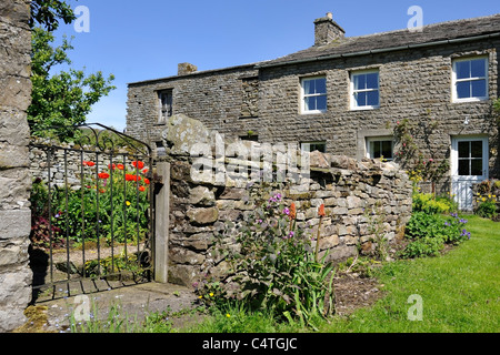 Mur de pierres sèches qui marque la frontière d'un village jardin dans Thwaite, Swaledale, Yorkshire, Angleterre Banque D'Images