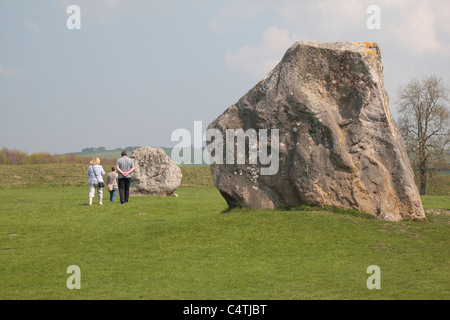 Visiteurs marchant à côté du cercle intérieur des menhirs. Une partie de l'Avebury Henge & Stone Circles site, Wiltshire, Angleterre. Banque D'Images