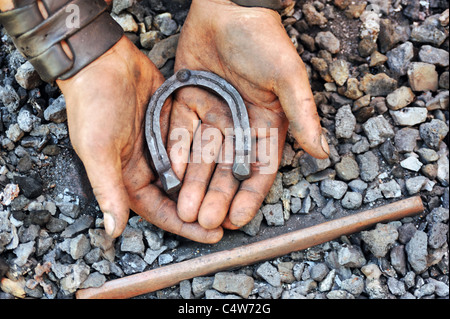 Détail de dirty hands holding horseshoe - blacksmith Banque D'Images