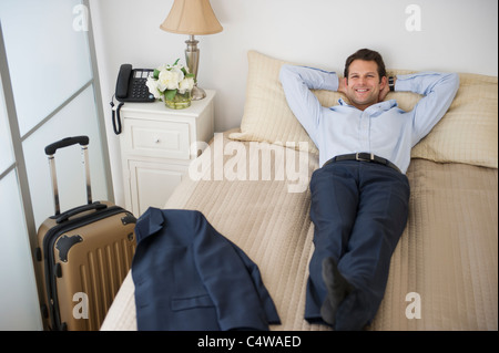 USA,New Jersey, Jersey City, businessman relaxing on bed in hotel room Banque D'Images