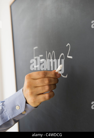 Close-up of man's hand writing formule la théorie de la relativité sur tableau noir Banque D'Images