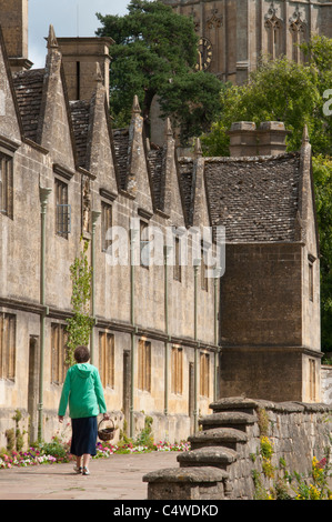 Une femme marche dernières hospices près de St James Church, Chipping Campden, dans le Worcestershire Cotswolds. UK Banque D'Images