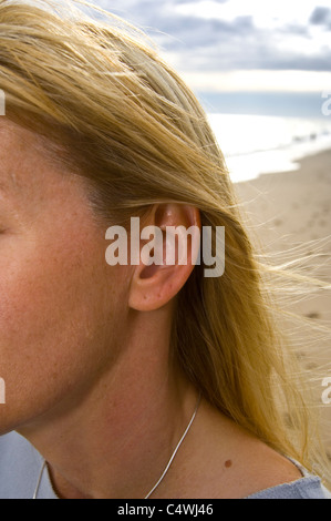 Du côté de femme montrant le visage avec de longs cheveux blonds sur la plage. Banque D'Images