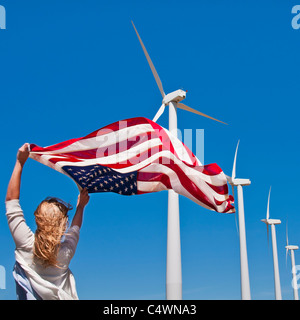 USA, California, Palm Springs, Femme tissant drapeau américain avec les éoliennes en arrière-plan Banque D'Images