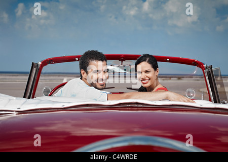 Petit ami et petite amie assis en voiture d'époque et s'étreindre à La Havane, Cuba. Vue de côté, de forme horizontale, copy space Banque D'Images