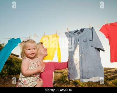 USA,California,Ladera Ranch,Mère avec sa fille (12-17 mois) étendre le linge sur la corde à linge Banque D'Images