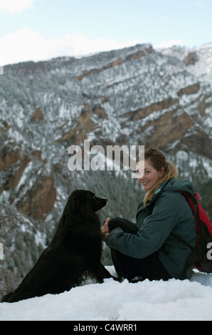 USA,Californie,jeune femme et chien assis on snowy hill Banque D'Images