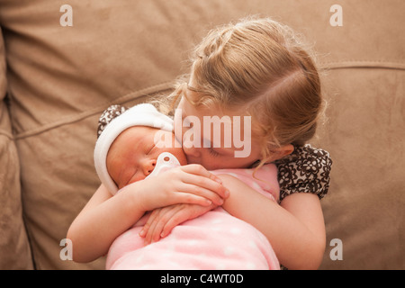 USA, Utah, Léhi, Girl (2-3) embracing baby sister sur canapé Banque D'Images