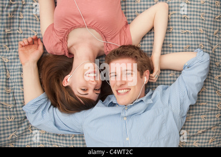 USA, Utah, Provo, Young couple with mp3 player lying on blanket Banque D'Images