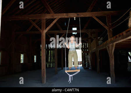 USA,New York,Dorset,femme on swing in barn Banque D'Images