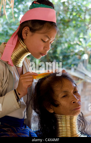 Une femme Paduang Karen de Birmanie portant des anneaux d'or autour de son cou se peignant les cheveux de sa mère dans un camp de réfugiés en Thaïlande. Banque D'Images