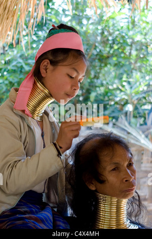 Une femme Paduang Karen de Birmanie portant des anneaux d'or autour de son cou se peignant les cheveux de sa mère dans un camp de réfugiés en Thaïlande. Banque D'Images