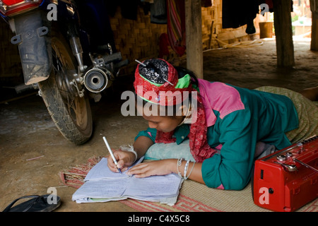 Une femme réfugiée Karen Paduang portant des anneaux d'or autour de son cou est étudiant à son domicile dans un camp de réfugiés birmans en Thaïlande. Banque D'Images