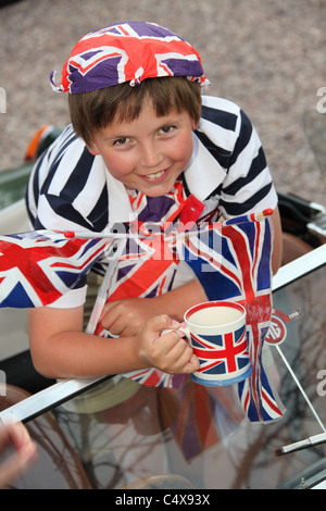 Jeune garçon tout en souriant orné de drapeaux Union Jack britannique et d'autres drogues. Banque D'Images