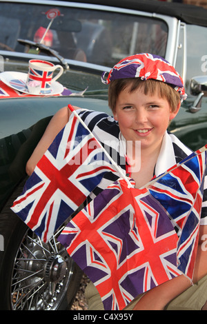 Jeune garçon tout en souriant orné de drapeaux Union Jack britannique et d'autres drogues. Banque D'Images