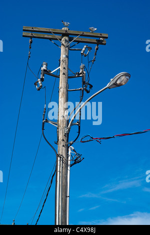 Un désordre alambiqué de fils et câbles de fond un poteau téléphonique en bois et lampe de rue. Banque D'Images