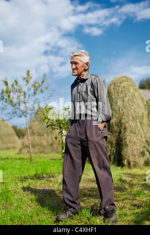 Portrait d'un agriculteur sur une prairie avec des meules de foin en arrière-plan Banque D'Images