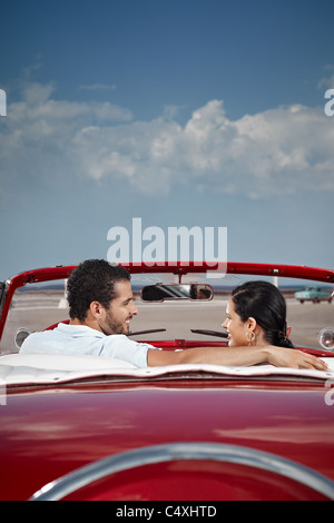 Petit ami et petite amie assis en voiture d'époque et s'étreindre à La Havane, Cuba. La forme verticale, vue arrière, copy space Banque D'Images