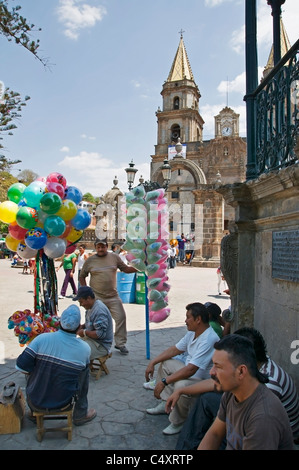 Un groupe de fournisseurs et amis se rassemblent à l'ombre pour se reposer sur la place en face de l'église lors d'un festival à Talpa. Banque D'Images