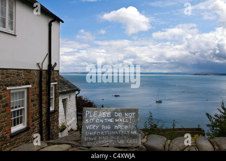 Le Signe de danger, 'ne pas s'asseoir sur ce mur", risque de chute de mur de pierre dans l'historique village de pêcheurs dans le Nord du Devon Clovelly UK Banque D'Images