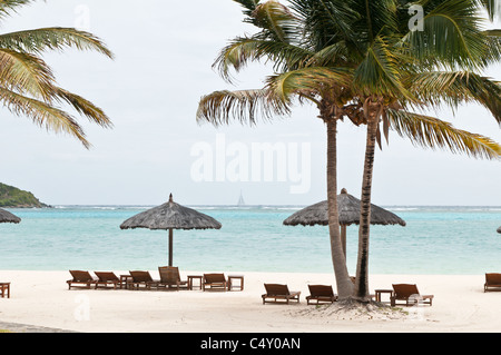 Chaises de plage et parasols au Canouan Estate Resort & Villas à Carenage Bay, île de Canouan, Saint-Vincent-et-les Grenadines. Banque D'Images