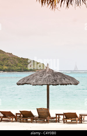 Chaises de plage et parasols au Canouan Estate Resort & Villas à Carenage Bay, île de Canouan, Saint-Vincent-et-les Grenadines. Banque D'Images