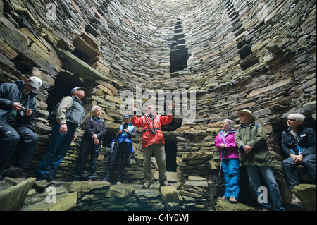 Vinnie historien Butler explique histoire de Broch de Mousa, ca 100 BC, le plus beau bâtiment préhistorique en Europe. Mousa, Shetland Banque D'Images