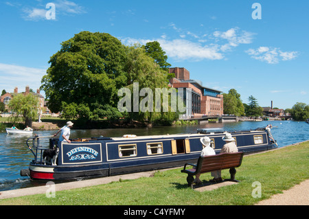 Un couple profiter du soleil au bord de la rivière Avon, à Stratford avec RSA theatre en arrière-plan. UK Banque D'Images