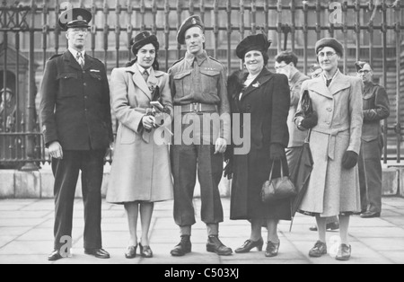 Un soldat de la seconde guerre mondiale reçoit une médaille militaire se tient à l'extérieur des portes à Buckingham Palace avec sa famille. Banque D'Images