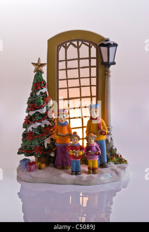 Carol singers en dehors d'une fenêtre éclairée. Décoration de Noël. Banque D'Images