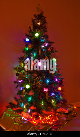 Arbre de Noël avec des lumières et présente autour de la base. Banque D'Images