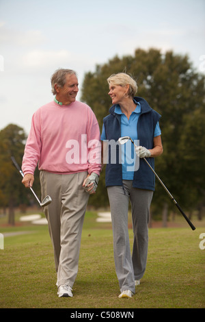 Caucasian couple walking on golf course Banque D'Images