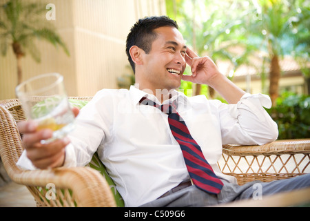 Smiling mixed race man drinking on patio Banque D'Images