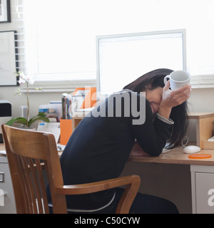 Hispanic woman working in office de boire du café Banque D'Images